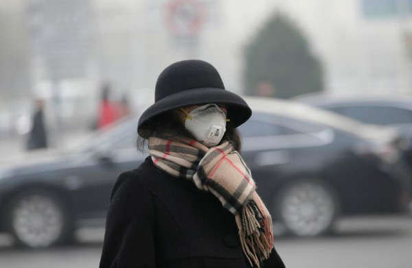Một người phụ nữ đeo khẩu trang đi trên đường trong khi sương khói nặng bao trùm Bắc Kinh sau khi thành phố này đưa ra cảnh báo ô nhiễm không khí đầu tiên trong mùa đông tại , Trung Quốc vào ngày 26/11/2018. Ảnh: Jason Lee