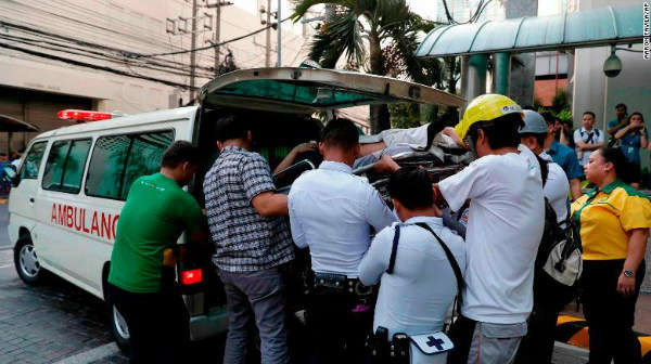 Những người công nhân chuyển một nhân viên đến xe cứu thương do nhân viên này bị chóng mặt khi trận động đất xảy ra ở Manila