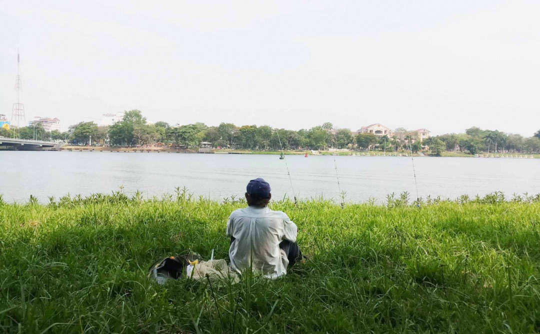 Một người dân tranh thủ vừa nghỉ mát ở ven sông Hương vừa câu cá thư giãn