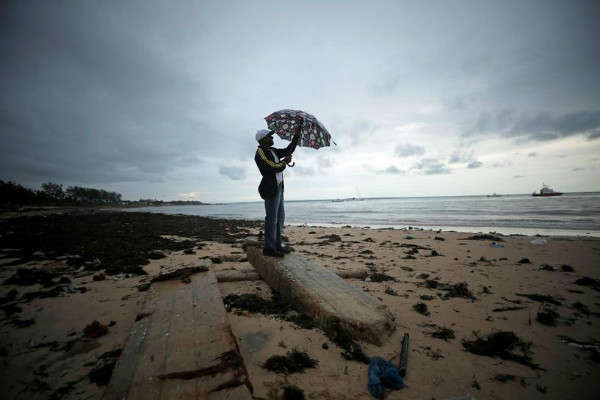 Người đàn ông cầm ô bên dưới những đám mây bão trên bãi biển Wimbe khi khu vực này chuẩn bị đón lượng mưa lớn hơn sau bão Kenneth ở Pemba Mozambique vào ngày 27/4/2019. Ảnh: Reuters/Mike Hutchings