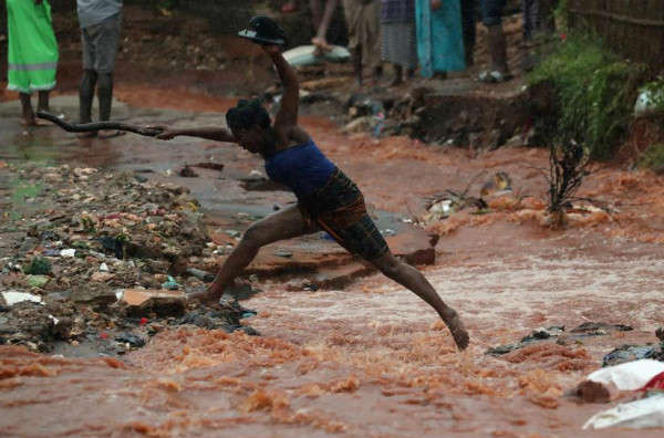 Người phụ nữ nhảy qua một con đường ngập lụt do mưa lớn trong  bão Kenneth ở Pemba, Mozambique vào ngày 28/4/2019. Ảnh: Reuters / Mike Hutchings