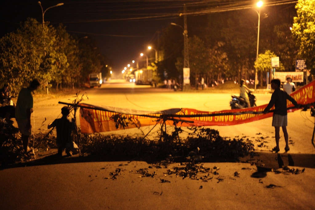 Người dân đã dùng cành cây, băng rôn chắn gần hết lòng đường khiến các xe tải chở hàng không thể ra và vào Khu công nghiệp Quảng Phú