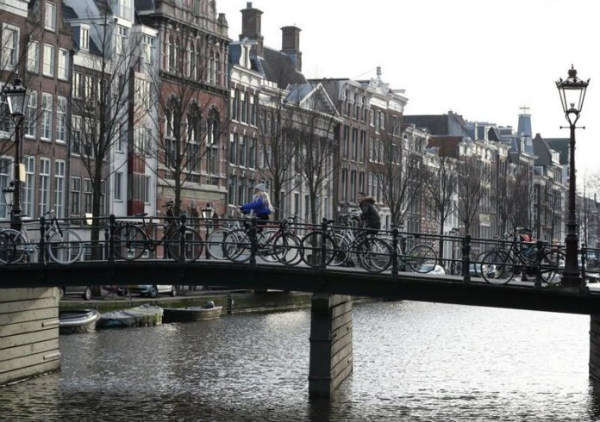 Mọi người đạp xe qua cầu ở trung tâm Amsterdam, Hà Lan vào ngày 29/1/2019. Ảnh: Reuters / Yves Herman
