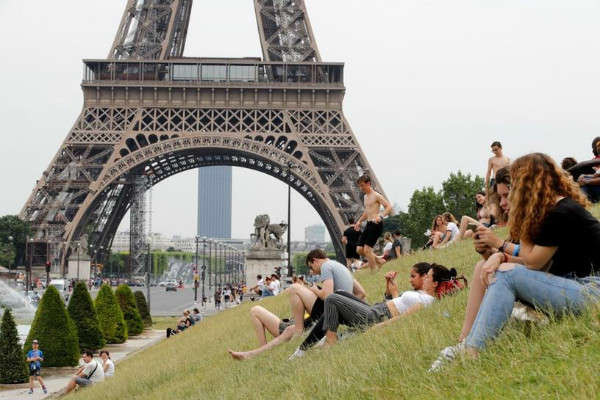 Người dân tắm nắng gần đài phun nước Trocadero và tháp Eiffel ở Paris khi một đợt nắng nóng theo dự báo ngày 24/6/2019 sẽ xảy ra ở nhiều khu vực của Pháp. Ảnh: Reuters / Philippe Wojazer