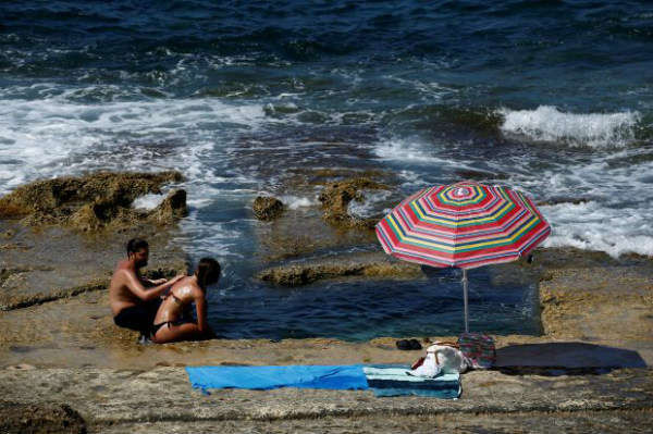 Mọi người tìm cách hạ nhiệt trên một bãi biển khi nắng nóng càn quét châu Âu ở Sliema, Malta vào ngày 26/6/2019. Ảnh: Reuters / Darrin Zammit Lupi