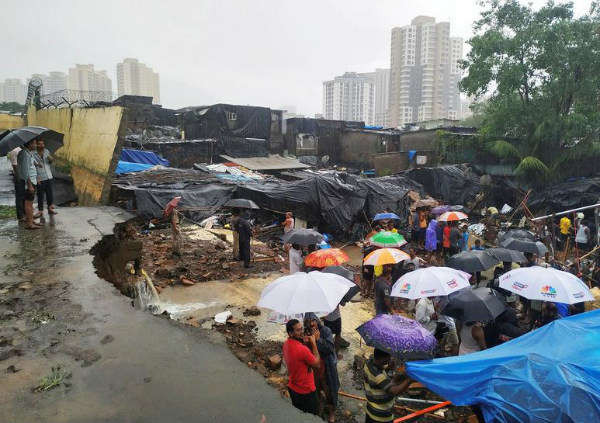 Mọi người đứng giữa các mảnh vỡ sau khi một bức tường đổ vào các túp lều do mưa lớn ở Mumbai, Ấn Độ vào ngày 2/7/2019. Ảnh: Reuters / Prashant Waydande