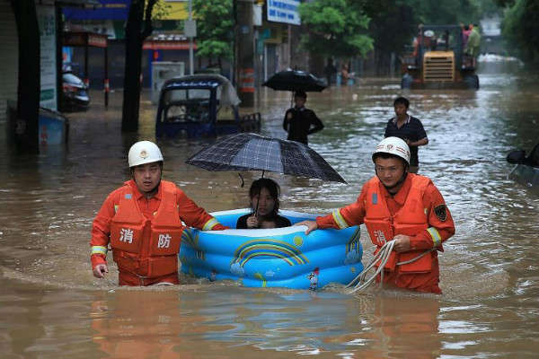Nhân viên cứu hộ lội qua vùng nước lũ khi họ sơ tán một người phụ nữ với một bể bơi bơm hơi trên đường phố sau khi mưa lớn ở Pingxiang, tỉnh Giang Tây, Trung Quốc vào ngày 9/7/2019. Ảnh: Reuters / Stringer