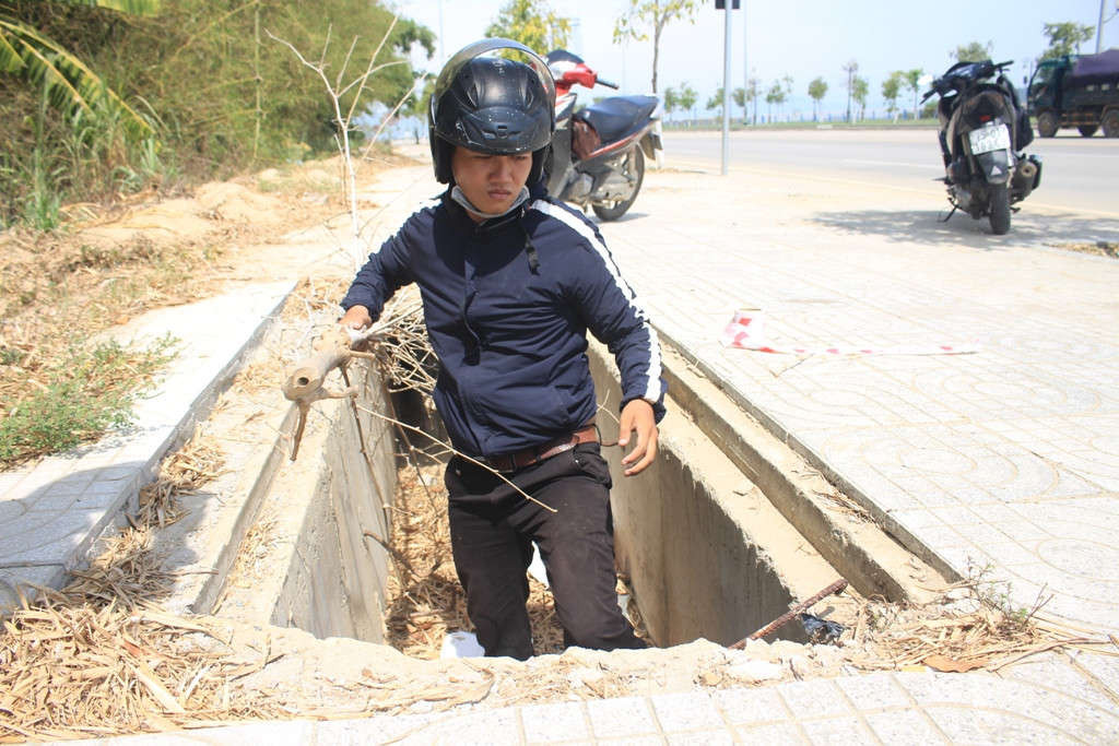Một nhân viên Công ty CP XD GT Quảng Ngãi dùng nhánh tre để che chắn tạm một số hố