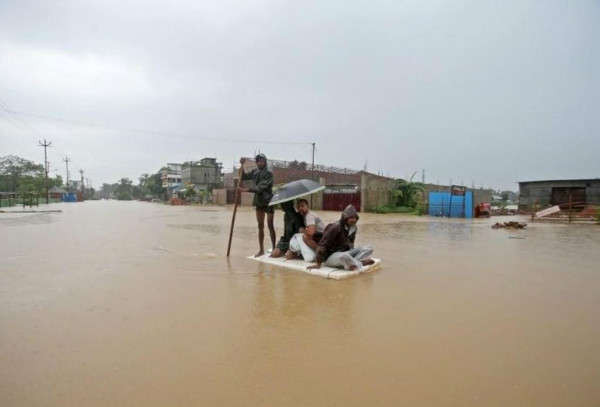 Dân làng sử dụng một chiếc bè tạm thời để băng qua khu vực bị ngập lụt ở ngoại ô Agartala, Ấn Độ vào ngày 15/7/2019