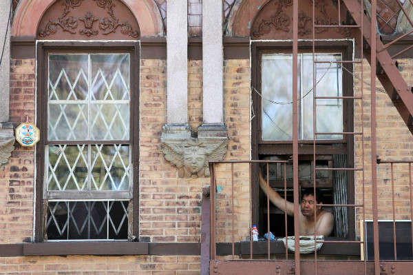 Một người đàn ông nhìn ra ngoài cửa sổ căn hộ Lower East Side khi sóng nhiệt tiếp tục ảnh hưởng đến khu vực ở Manhattan, thành phố New York, New York, Mỹ vào ngày 21/7/2019. Ảnh: Reuters/ Andrew Kelly