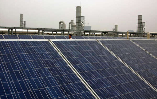 Người công nhân đi sau các tấm pin mặt trời trên mái nhà xưởng của Công ty Năng lượng Xanh Yingli, nằm ở thành phố Bảo Định, tỉnh Hà Bắc vào ngày 20/6/2011. Ảnh: Reuters / David Gray