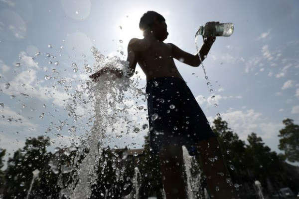 Một cậu bé chơi với nước trong đài phun nước vào một ngày hè nóng nực ở Brussels, Bỉ, 25/7/2019. Ảnh: REUTERS/Yves Herman
