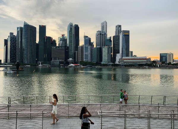 Người qua đường sử dụng điện thoại trước hình ảnh đường chân trời của khu thương mại trung tâm của Singapore vào ngày 10/5/2019. Ảnh: Kevin Lam