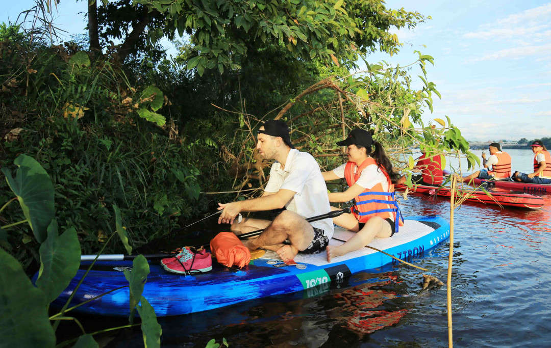 Khách du lịch chèo thuyền dọn rác trên sông Hương