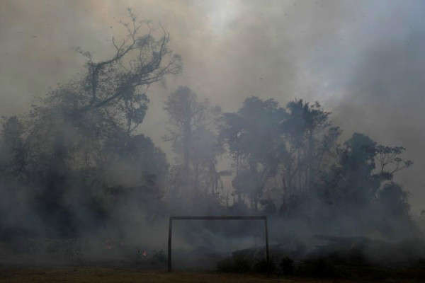 Ngọn lửa thiêu rụi một khu rừng rậm Amazon khi nó bị những người khai thác gỗ và nông dân “dọn sạch” đằng sau một sân bóng ở Porto Velho, Brazil vào ngày 27/8/2019. Ảnh: Reuters / Ricardo Moraes