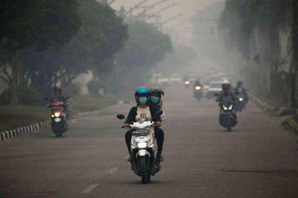 Người đi xe máy qua khói mù do cháy rừng ở Palangka Raya, tỉnh Trung Kalimantan trên đảo Borneo, Indonesia vào ngày 15/9/2019. Ảnh: Reuters / Willy Kurniawan
