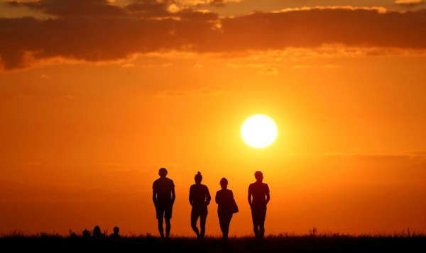Bốn người đứng đối diện với mặt trời lặn ở đỉnh Drachenberg ở Berlin, Đức vào ngày 19/8/2019. Ảnh: Reuters