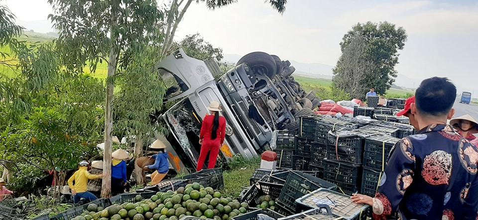 Người dân giúp tài xế xe tải nhặt lại trái cây bị đổ xuống ruộng và lề đường