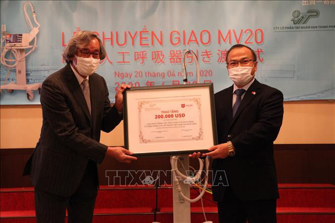 Đại sứ Vũ Hồng Nam (bên phải) đại diện cho nhà tài trợ trao 200.000 USD cho ông Trần Ngọc Phúc, Chủ tịch HĐQT Metran kiêm Chủ tịch Hội người Việt Nam tại Nhật Bản. Ảnh: Đức Thịnh/PV TTXVN tại Nhật Bản